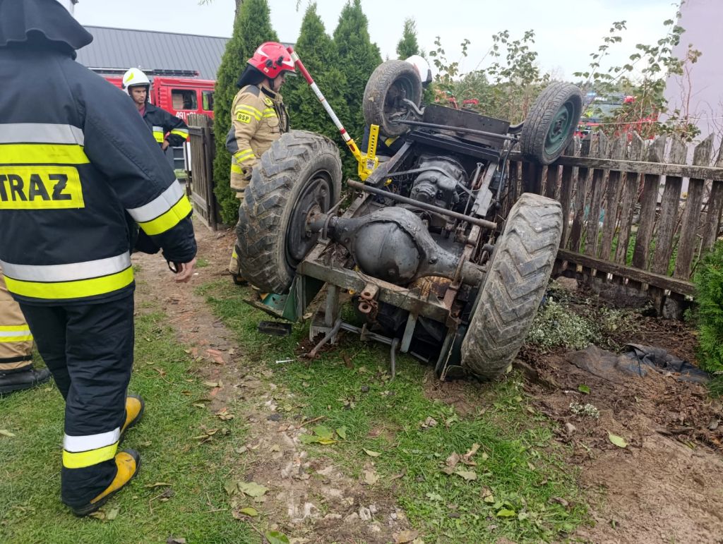 wypadek, wywrócony ciągnik, ranny mężczyzna, przygniecenie