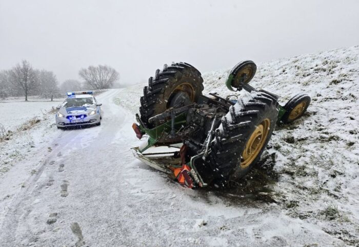 Ciągnik z zaczepioną przyczepą z drewnem wpadł w poślizg na oblodzonej drodze. W efekcie tego maszyna dachowała. Fot. KPP Staszów